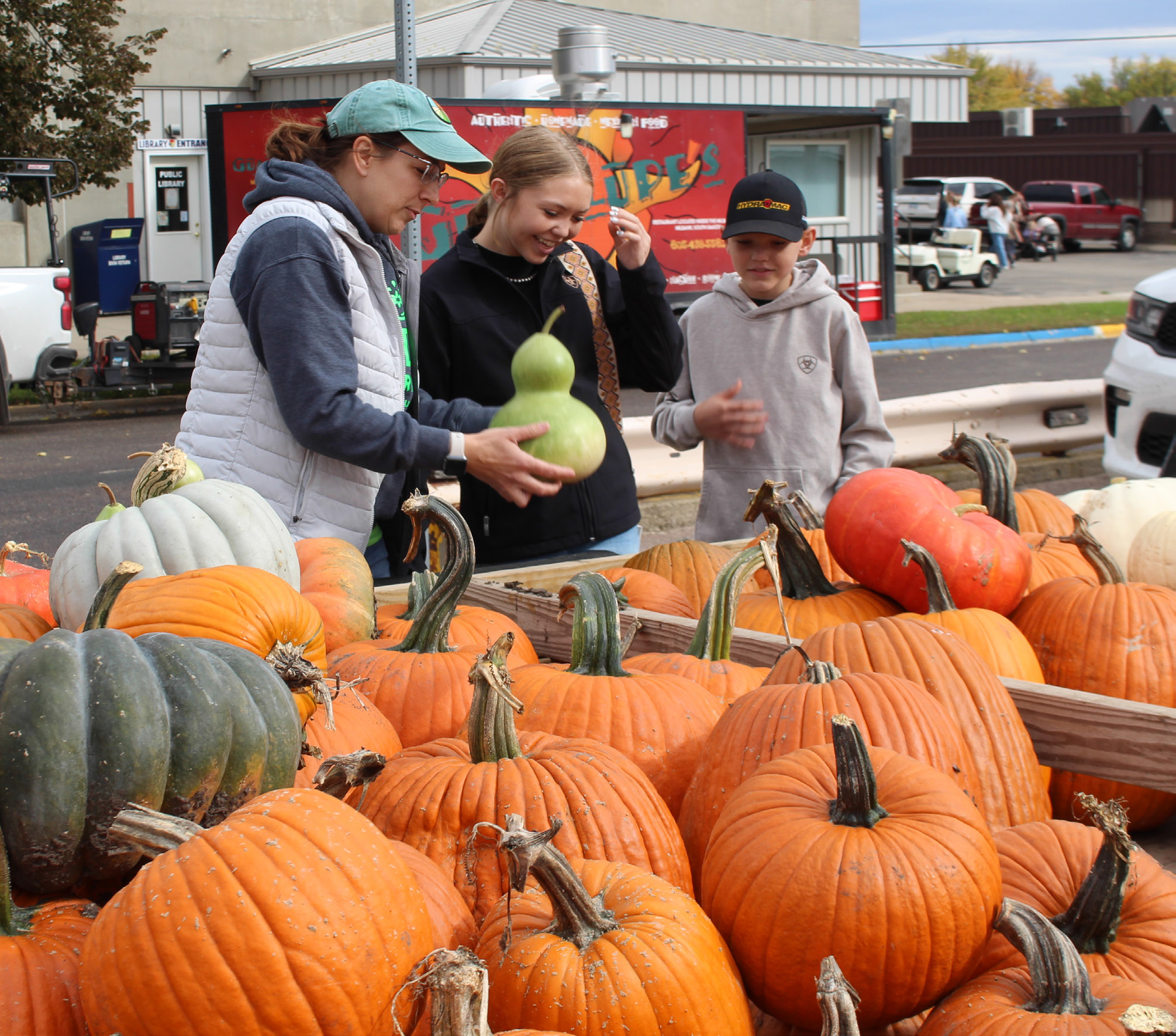 Melissa Waldner, left, helps Mallory Snaza center, and Owen Snaza, right, pick pumpkins to take home Oct. 3 at Pumpkin Fest in Webster. Reporter &amp; Farmer | Timothy Gibson