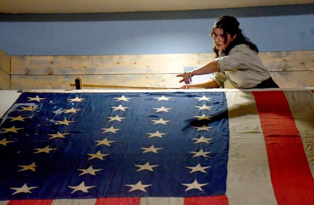 Sitting on display for 12 years has caused the last flag flown over Fort Sisseton to collect a bit of dust. Here, Mia Higginbotham, a summer intern at Fort Sisseton Historic State Park who is studying textile conservation at Arizona State University. Reporter &amp; Farmer | Timothy Gibson