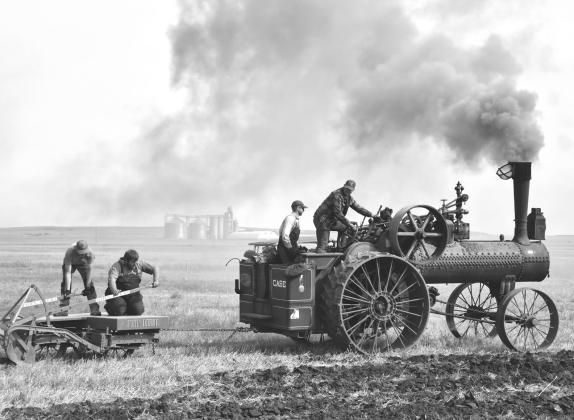 John Kirby, right, drives the 1919 40-horsepower Case steam traction engine in the plow demonstration Sept. 12 in Andover. Next to Kirby is fireman Miles McDaniel, responsible for feeding fuel into the engine and maintaining steam pressure. Manning the plow are Dawson Larson, left, and Jordan Schmieg, second from left. Reporter &amp; Farmer | Timothy Gibson