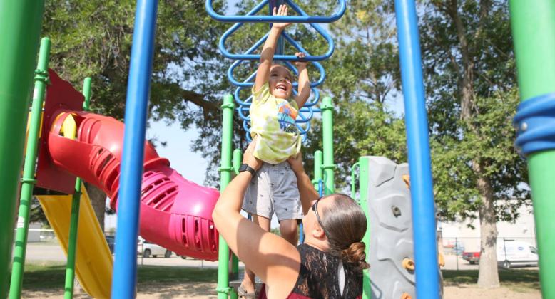 Jessica Eagle Star helps her son Noran across the monkey bars at the park in Winner Aug. 29, 2023. Reporter &amp;amp; Farmer | Makenzie Huber/South Dakota Searchlight
