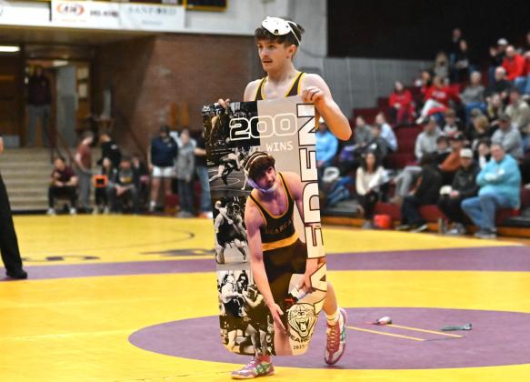 Webster Area senior wrestler Haeden Jorgenson holds up a banner memorializing his 200th varsity wrestling win during a tournament at Webster Armory Jan. 3. Jorgenson began wrestling in varsity matches in seventh grade and said he has his eyes set on a state title in his final year of high school after three previous runner-up finishes. Reporter &amp;amp; Farmer | Brianna Jorgenson, Captured Creations Photography
