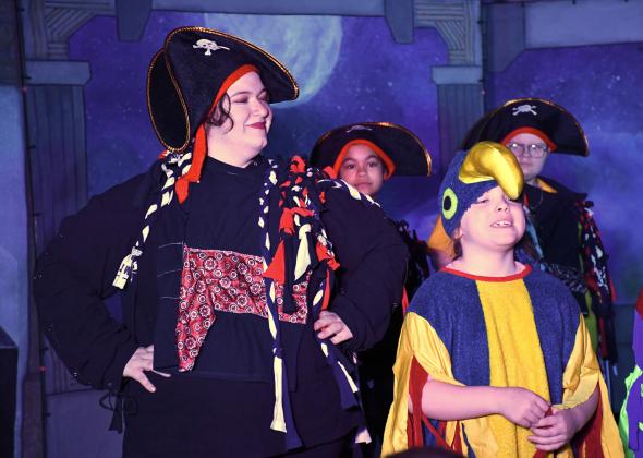 Webster Area first grader Vivian Garry, right, plays a parrot next to Theatre 605 actor/director Nessa Yaakova who plays a pirate during the school’s musical production of Space Pirates March 13 at Webster Area High School. The play was Webster Area’s sixth time hosting the touring theatre company who helps students put on a production with one week of preparation. Reporter &amp;amp; Farmer | Leyton Beardslee