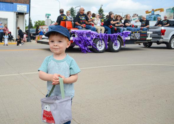 Two-year-old Boone Lesnar smiles after gathering a handful of candy tossed out by members of a Webster High School alumni class float June 27 for the alumni parade. He and many other children in town for the event were beneficiaries of the sweet treats class members tossed to onlookers. Lesnar is the son of Mike and Amber Lesnar of rural Webster. Reporter &amp; Farmer | Amanda Dulitz