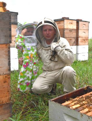 Will Marchuk and his three-year-old son Mark pose for a picture in one of Marchuk’s bee yards near Andover July 22. Marchuk is a commercial beekeeper who immigrated to the U.S. from Ukraine in 2009 and now operates over 4,200 hives. Reporter &amp;amp; Farmer | Leyton Beardslee
