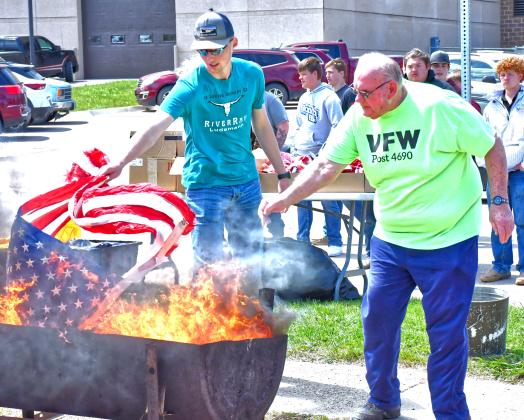 Webster Area School and Webster Veterans of Foreign Wars held a flag retirement ceremony May 8. Commander Kevin Bohn welcomed students and public members who were in attendance. From left, Gage Wik and Tom Lewno help burn flags as a way to show respect. Reporter &amp;amp; Farmer | Connor Handrahan