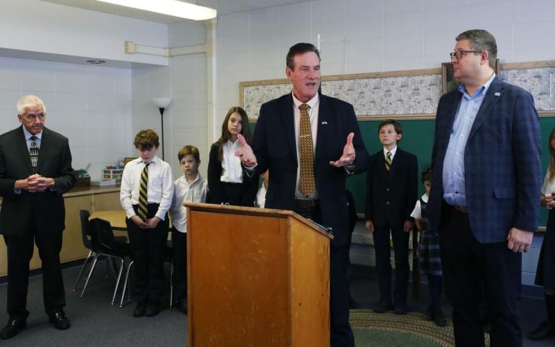 South Dakota Gov. Larry Rhoden speaks to media during an announcement at the St. Joseph Academy in Sioux Falls Nov. 11. State Education Secretary Joe Graves (left), Lt. Gov. Tony Venhuizen (right) and St. Joseph Academy students stand around him. Reporter &amp;amp; Farmer | Makenzie Huber for South Dakota Searchlight