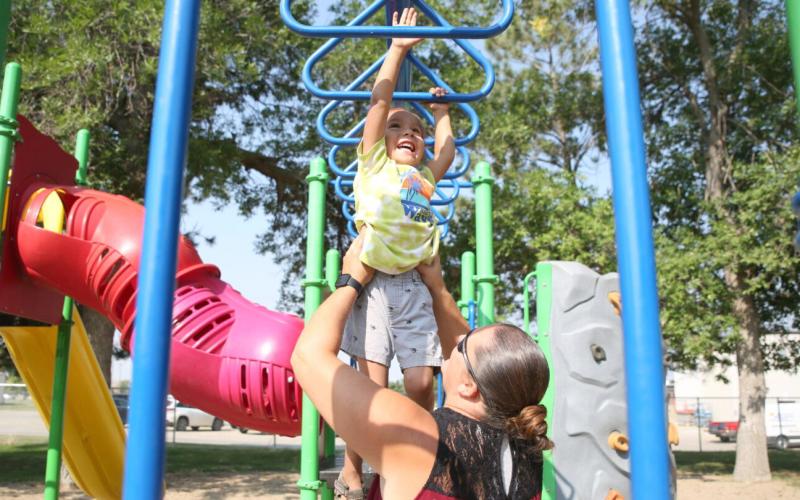 Jessica Eagle Star helps her son Noran across the monkey bars at the park in Winner Aug. 29, 2023. Reporter &amp;amp; Farmer | Makenzie Huber/South Dakota Searchlight