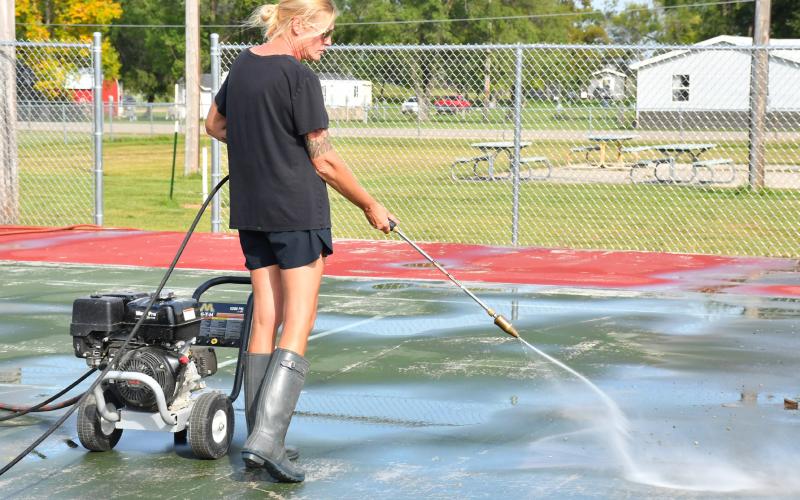 Tonya Niewald with Janco Athletic Surfacing works to clean off the tennis courts at Fred Haase Memorial Park in Webster in preparation for resurfacing. Webster Mayor Mike Grosek said the plan is to have one tennis court and two pickleball courts at the park. Reporter &amp;amp; Farmer | Leyton Beardslee