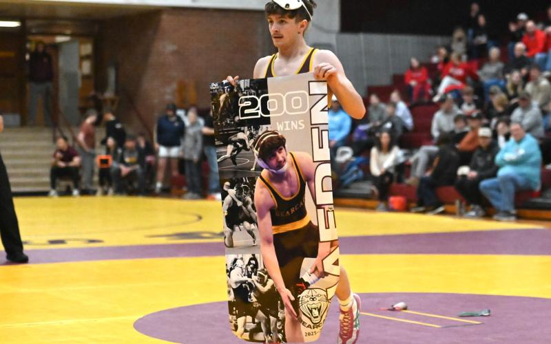 Webster Area senior wrestler Haeden Jorgenson holds up a banner memorializing his 200th varsity wrestling win during a tournament at Webster Armory Jan. 3. Jorgenson began wrestling in varsity matches in seventh grade and said he has his eyes set on a state title in his final year of high school after three previous runner-up finishes. Reporter &amp;amp; Farmer | Brianna Jorgenson, Captured Creations Photography