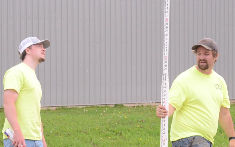 Nathan Palmer and Austin Gruba with Helms &amp;amp; Associates are pictured verifying base course on E. 3rd Ave. in Webster June 2 ahead of resurfacing the road. Reporter &amp;amp; Farmer | Annie Witt