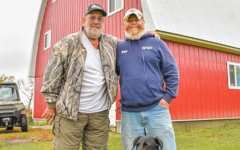 (At right) Webster area resident, from left, Bruce Knowlan, Josh Anderson, Webster and Knowlan’s dog Hazy pose in front of Knowlan’s historic gothic arch barn Oct. 14. The 1951 barn saw significant upgrades from 2015-16 including new siding and roof. Knowlan, who owns the barn with his wife Annie, employed the help of Anderson for the project. Reporter &amp;amp; Farmer | Leyton Beardslee