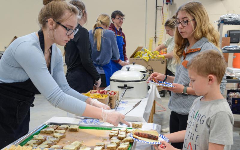 Webster Area High School 10th grader Delilah Buxton serves dessert to second grader Zane Hubsch and seventh grader Remi Hubsch April 25 during Webster Area High School’s open house which showed off the newly expanded CTE wing. The meal was prepared in part by students of the school’s culinary class for the public who toured the facility that evening. Reporter &amp;amp; Farmer | Amanda Dulitz