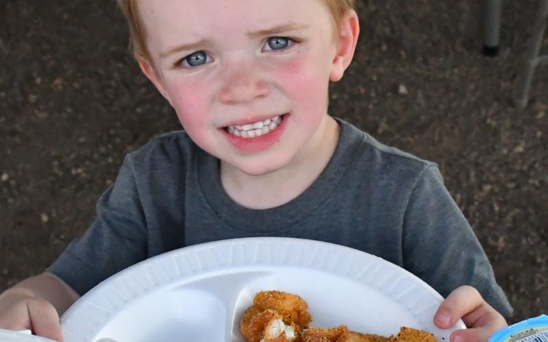 Nolan Andrews cheeses with his plate of fish at the grand opening of the Glacial Lakes Fish Cleaning Station in Webster. January 2024 the City of Webster approved to move forward with the station. Webster Area Chamber of Commerce president Katy Marx who has worked closely with the project stated, “The event turned out great. The support was amazing.” Reporter &amp;amp; Farmer | Annie Witt