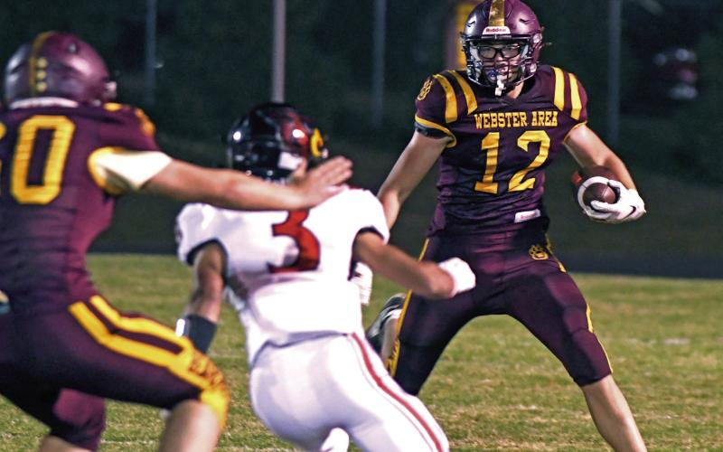 Jeron McCreary (12) looks for an opening while carrying the ball as a Deuel defensive player Axel Gallardo (3) looks to close his path during the home game Oct. 11 in Webster. Meanwhile Bearcat player Devin Snaza (60) looks to provide a block for McCreary. The Bearcats ultimately lost the game, 0-21 shutout against the Cardinals. Reporter &amp;amp; Farmer | Amanda Dulitz