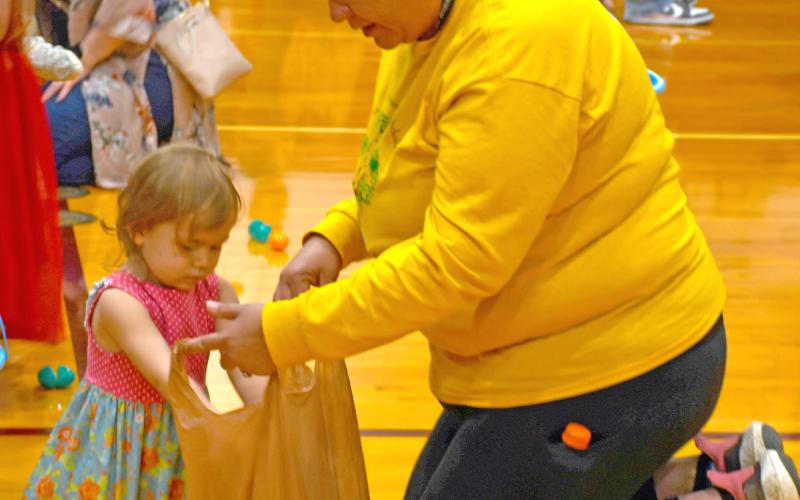 Taking part in the 18th annual Easter Eggs-travaganza April 19 at the Webster Armory was Aria Fellbaum. Meanwhile mom Jacquie Fellbaum helps hold a plastic bag for her to store her loot. The event is annually sponsored by First Baptist Church, Webster. Reporter &amp;amp; Farmer | Jessica Washenberger
