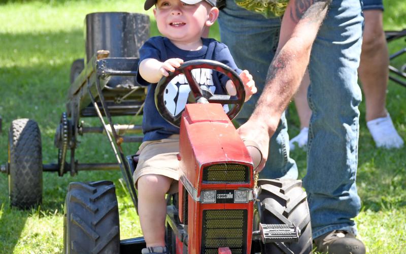 (At left) Weighing in at 19 months, Boone Lesnar of rural Webster takes his turn at doing the pedal tractor pull Aug. 9 during the Day County Fair. Lesnar is the son of Mike and Amber Lesnar. Russell Larson helps him along. Reporter &amp;amp; Farmer | Amanda Dulitz
