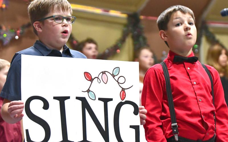 Webster Area third grade students, from left, Rhiley Zimmerman and Archer Chevalier sing during the school’s elementary winter concert Dec. 8 at the Webster Armory. Reporter &amp;amp; Farmer | Leyton Beardslee