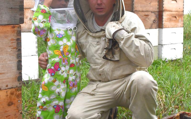 Will Marchuk and his three-year-old son Mark pose for a picture in one of Marchuk’s bee yards near Andover July 22. Marchuk is a commercial beekeeper who immigrated to the U.S. from Ukraine in 2009 and now operates over 4,200 hives. Reporter &amp;amp; Farmer | Leyton Beardslee