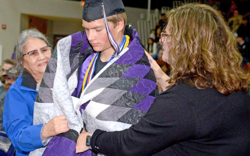 At Waubay High School’s graduation, certain members of the class of 2025 received star quilts to celebrate their accomplishments. Here, Sandi Bernard helps wrap a quilt around graduate Dylan Rumpza while his mom Deb Rumpza also helps wrap the fabric around his shoulders. Waubay saw 12 seniors cross the stage and turn their tassels May 17 at Waubay High School gym. Rumpza was the class salutatorian. Reporter &amp;amp; Farmer | Amanda Dulitz