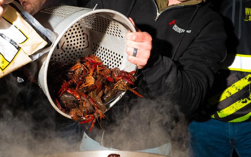 At left, Riley Reetz dumps a bucket of crawfish into a boiling pot of water during the crawfish boil fundraiser in Webster April 3. Proceeds from the event will go towards new playground equipment for Haase Baseball Field, according to organizers. This was the 11th year for the annual event, traditionally held on Good Friday. This was the first year the event was hosted by the Crawfish Committee. Reporter &amp;amp; Farmer photo by Leyton Beardslee