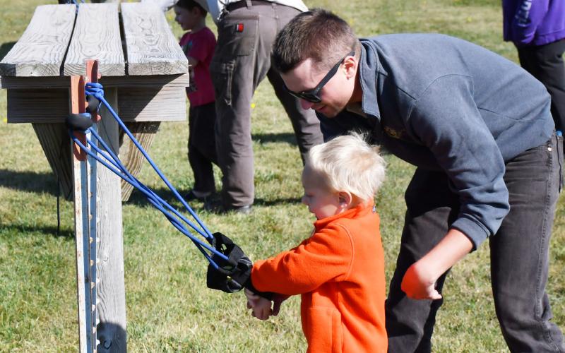 With the help of the South Dakota Game Fish and Parks park manager Jacob De-Baun, three-year-old Joseph Tonsfeldt launches apples from a sling shot at the Fort Sisseton Harvest Festival Sept. 21. Tonsfeldt came to the annual harvest fest with his grandmother Mari Abler who is from Norfolk, NE. Reporter &amp;amp; Farmer | Brenner Cariveau