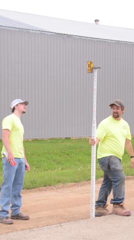 Nathan Palmer and Austin Gruba with Helms &amp; Associates are pictured verifying base course on E. 3rd Ave. in Webster June 2 ahead of resurfacing the road. Reporter &amp; Farmer | Annie Witt