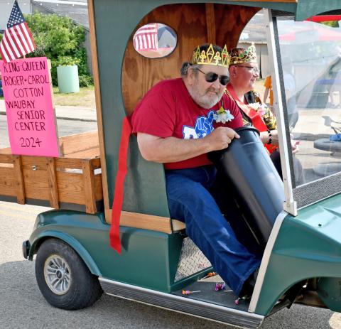 Roger and Carol Cotton were crowned the 2024 Waubay Senior Center King and Queen and were celebrated by participating in the parade during Waubay’s Fun Fest July 20. Here, Roger Cotton reaches into a bucket to pull out more candy to toss to eager parade goers. Reporter &amp; Farmer | Amanda Dulitz