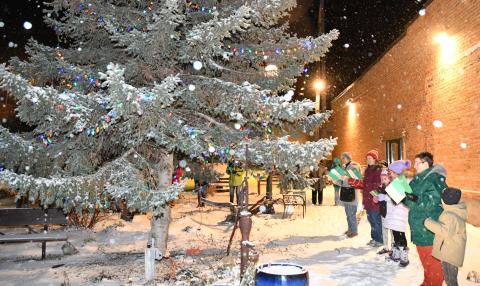 A group gathers around the large evergreen tree in the center of the Day County Arts Council’s mural garden and sings Christmas carols just moments after the official first lighting of the tree Dec. 1. From right are Ronan Smidt, Tandra Smidt, Amara Pool, Aly Moos, Jennifer Moos and Sandra Rood. Reporter &amp; Farmer | Amanda Dulitz