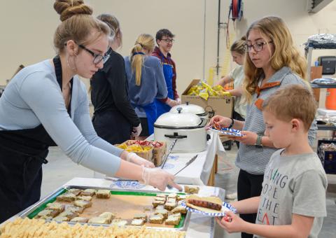 Webster Area High School 10th grader Delilah Buxton serves dessert to second grader Zane Hubsch and seventh grader Remi Hubsch April 25 during Webster Area High School’s open house which showed off the newly expanded CTE wing. The meal was prepared in part by students of the school’s culinary class for the public who toured the facility that evening. Reporter &amp; Farmer | Amanda Dulitz