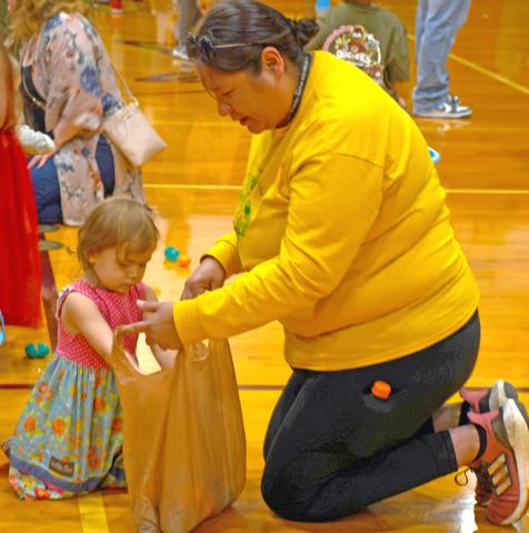 Taking part in the 18th annual Easter Eggs-travaganza April 19 at the Webster Armory was Aria Fellbaum. Meanwhile mom Jacquie Fellbaum helps hold a plastic bag for her to store her loot. The event is annually sponsored by First Baptist Church, Webster. Reporter &amp; Farmer | Jessica Washenberger