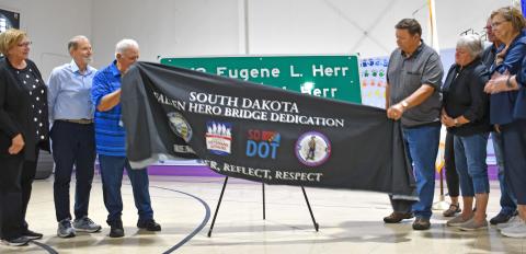 Members of the Herr family unveil the sign at an event at the Bristol gym last week, dedicated to the Herr brothers who died in the line of duty during World War II. From left are Susan (Herr) Hanson, Doug Herr, Rick Herr, Gene Herr, Karen (Herr) Kaml,Steve Hanson and Jackie (Herr) Hanson. Reporter &amp; Farmer | Annie Witt