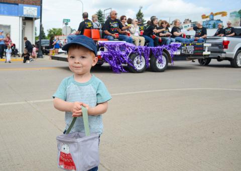 Two-year-old Boone Lesnar smiles after gathering a handful of candy tossed out by members of a Webster High School alumni class float June 27 for the alumni parade. He and many other children in town for the event were beneficiaries of the sweet treats class members tossed to onlookers. Lesnar is the son of Mike and Amber Lesnar of rural Webster. Reporter &amp; Farmer | Amanda Dulitz