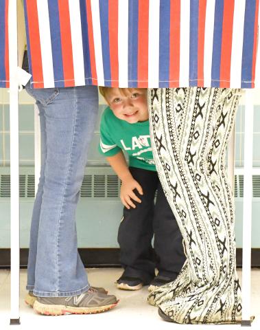 Four-year-old Colton Carlson peeks out from under the privacy curtain of the voting booth where his mom Crystal Carlson was casting her ballot in the June 4 primary. Crystal Carlson brought both kids, Colton and older sister Charley, 10, to the polls at the Day County Courthouse that day so they could learn about the voting process. Reporter &amp; Farmer | Amanda Dulitz