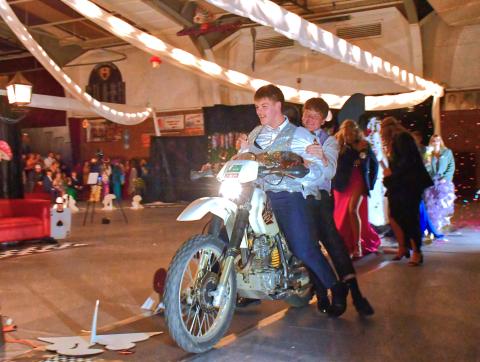 (Above) From left, Jack Snell and TJ Sonstebo start off the comedy side of the Grand March by driving through the armory on a motor-bike. Webster Area’s Grand March was turning into a confetti-water- bubble mess with students laughing as they entertained the crowd. Reporter &amp; Farmer | Connor Handrahan