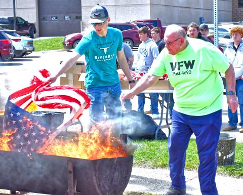 Webster Area School and Webster Veterans of Foreign Wars held a flag retirement ceremony May 8. Commander Kevin Bohn welcomed students and public members who were in attendance. From left, Gage Wik and Tom Lewno help burn flags as a way to show respect. Reporter &amp; Farmer | Connor Handrahan