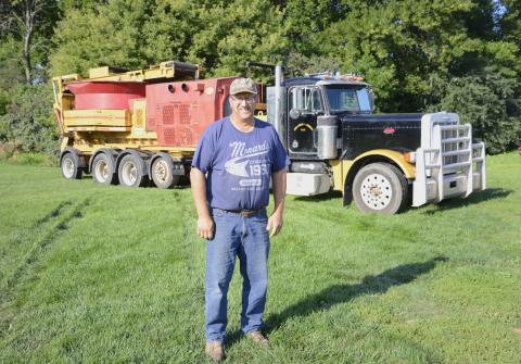 Mike Meland, owner/operator of Meland Haygrinding LLC, stands in his farmyard in southern Day County with one of his truck-mounted hay grinders seen in the background. Meland has been running the business since 2006 with the help of his wife Jennifer and their four kids.