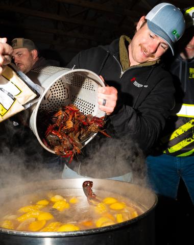At left, Riley Reetz dumps a bucket of crawfish into a boiling pot of water during the crawfish boil fundraiser in Webster April 3. Proceeds from the event will go towards new playground equipment for Haase Baseball Field, according to organizers. This was the 11th year for the annual event, traditionally held on Good Friday. This was the first year the event was hosted by the Crawfish Committee. Reporter &amp; Farmer photo by Leyton Beardslee