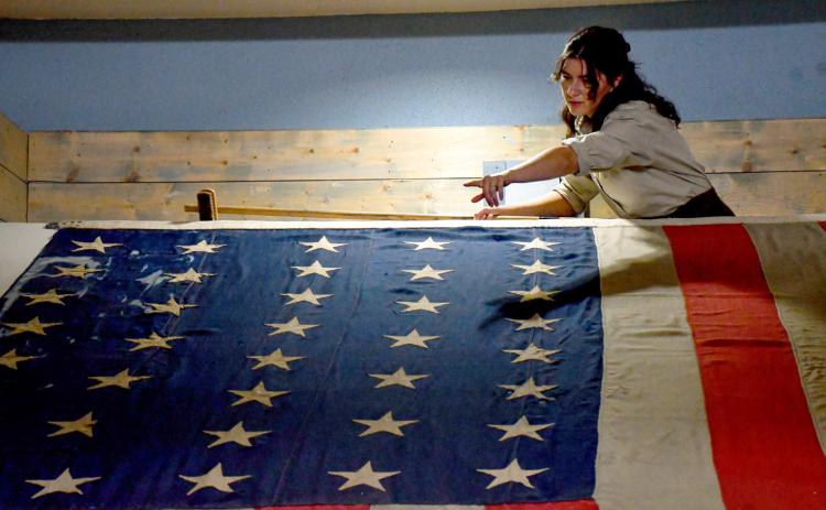 Sitting on display for 12 years has caused the last flag flown over Fort Sisseton to collect a bit of dust. Here, Mia Higginbotham, a summer intern at Fort Sisseton Historic State Park who is studying textile conservation at Arizona State University. Reporter &amp; Farmer | Timothy Gibson