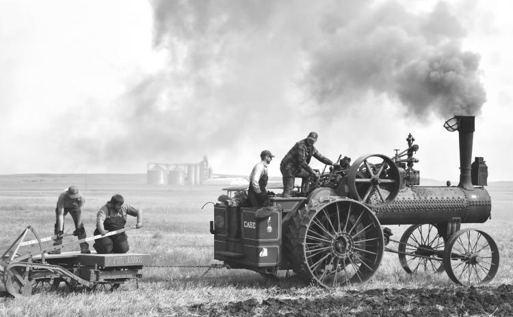 John Kirby, right, drives the 1919 40-horsepower Case steam traction engine in the plow demonstration Sept. 12 in Andover. Next to Kirby is fireman Miles McDaniel, responsible for feeding fuel into the engine and maintaining steam pressure. Manning the plow are Dawson Larson, left, and Jordan Schmieg, second from left. Reporter &amp; Farmer | Timothy Gibson