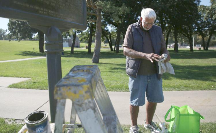 Jim Carlson, with the Minnehaha County Historical Society, repaints a historical marker at Falls Park in Sioux Falls Sept. 23. Reporter &amp; Farmer | Makenzie Huber/South Dakota Searchlight