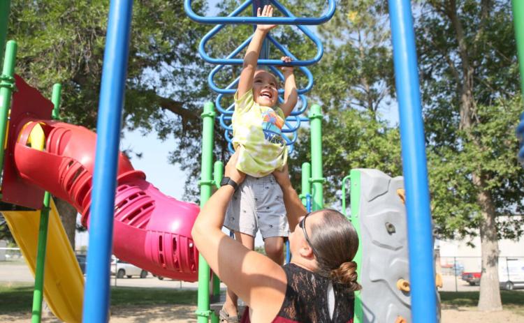 Jessica Eagle Star helps her son Noran across the monkey bars at the park in Winner Aug. 29, 2023. Reporter &amp; Farmer | Makenzie Huber/South Dakota Searchlight