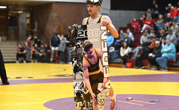 Webster Area senior wrestler Haeden Jorgenson holds up a banner memorializing his 200th varsity wrestling win during a tournament at Webster Armory Jan. 3. Jorgenson began wrestling in varsity matches in seventh grade and said he has his eyes set on a state title in his final year of high school after three previous runner-up finishes. Reporter &amp; Farmer | Brianna Jorgenson, Captured Creations Photography