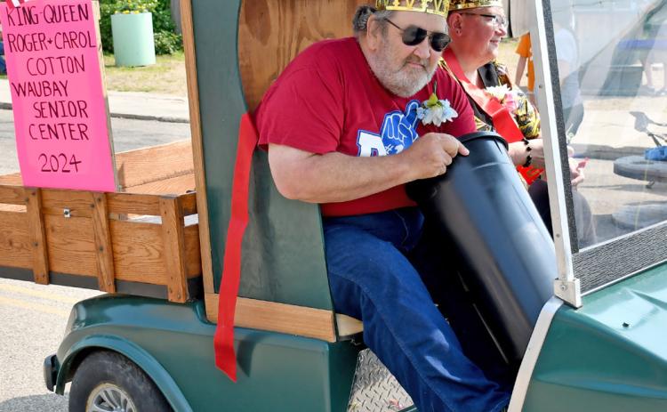 Roger and Carol Cotton were crowned the 2024 Waubay Senior Center King and Queen and were celebrated by participating in the parade during Waubay’s Fun Fest July 20. Here, Roger Cotton reaches into a bucket to pull out more candy to toss to eager parade goers. Reporter &amp; Farmer | Amanda Dulitz