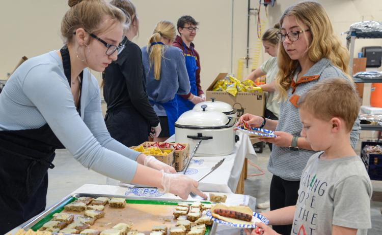 Webster Area High School 10th grader Delilah Buxton serves dessert to second grader Zane Hubsch and seventh grader Remi Hubsch April 25 during Webster Area High School’s open house which showed off the newly expanded CTE wing. The meal was prepared in part by students of the school’s culinary class for the public who toured the facility that evening. Reporter &amp; Farmer | Amanda Dulitz
