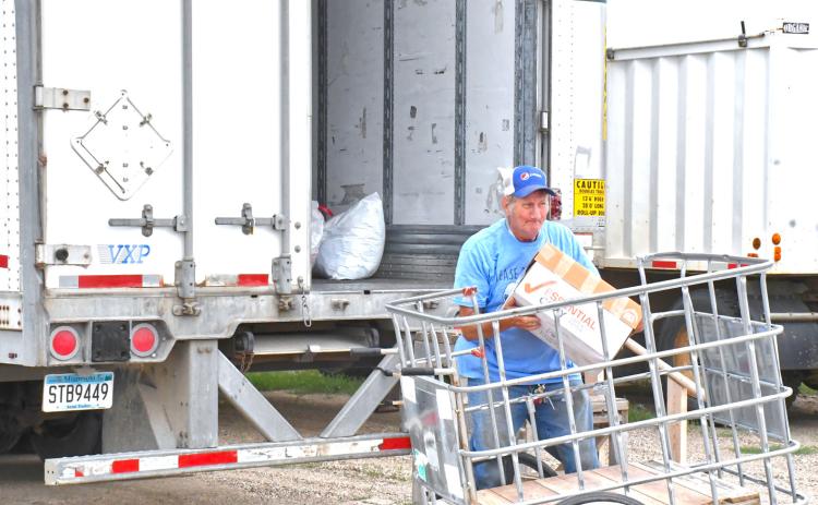 In last week’s issue, an article was published about a mysterious trailer that appeared in the farmer market’s parking lot and with help from a few community members, the trailer has been identified. Needs Anonymous has been using this trailer to collect their unsellable products and those donations will go to helping less fortunate people in Africa. Here, Howard Hvidsten can be seen loading items into the trailer. Reporter &amp; Farmer | Connor Handrahan