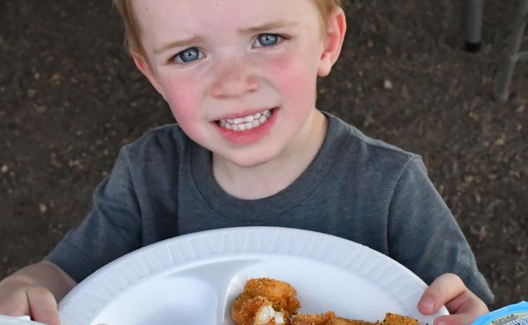 Nolan Andrews cheeses with his plate of fish at the grand opening of the Glacial Lakes Fish Cleaning Station in Webster. January 2024 the City of Webster approved to move forward with the station. Webster Area Chamber of Commerce president Katy Marx who has worked closely with the project stated, “The event turned out great. The support was amazing.” Reporter &amp; Farmer | Annie Witt