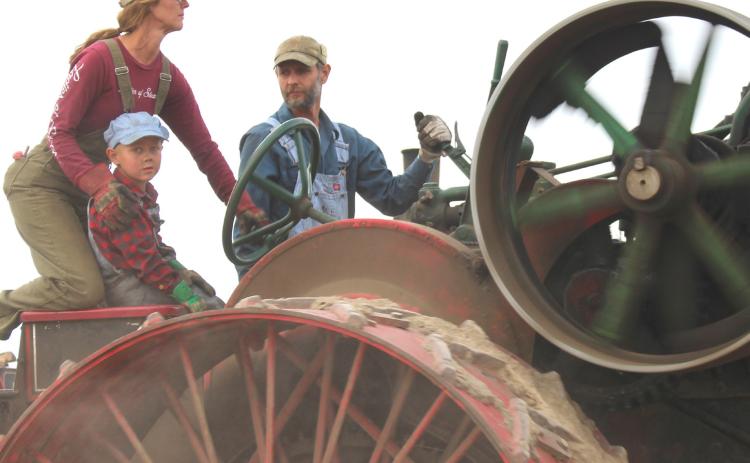 Jen Roth, left, drives an early 1920s 65-horsepower Case steam traction engine. Colt Edin, right, operates the gear shifter while Abram Edin, center, enjoys the ride Sept. 12 at Andover’s James Valley Threshing Show. See more photos throughout. Reporter &amp; Farmer | Timothy Gibson