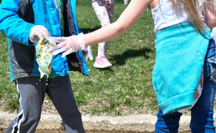 Levi Linde and Harlow Heupel, members of Webster Area Elementary kindergarden class, walked with classmates through the streets of Webster April 22 to clean up any garbage they found. Here, the pair work to clean up a sopping sandwich wrap which had gotten wet in the street. Reporter &amp; Farmer | Amanda Dulitz