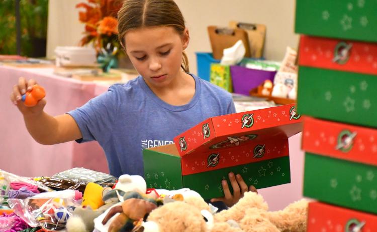 Naomi Acree, age eight, with Girl Scout Troop 50657 helps pack boxes for Operation Christmas Child at Westside Wesleyan Church in Bristol Nov. 13. Acree is the daughter of Mike and Jenny Acree, Webster. Reporter &amp; Farmer | Leyton Beardslee