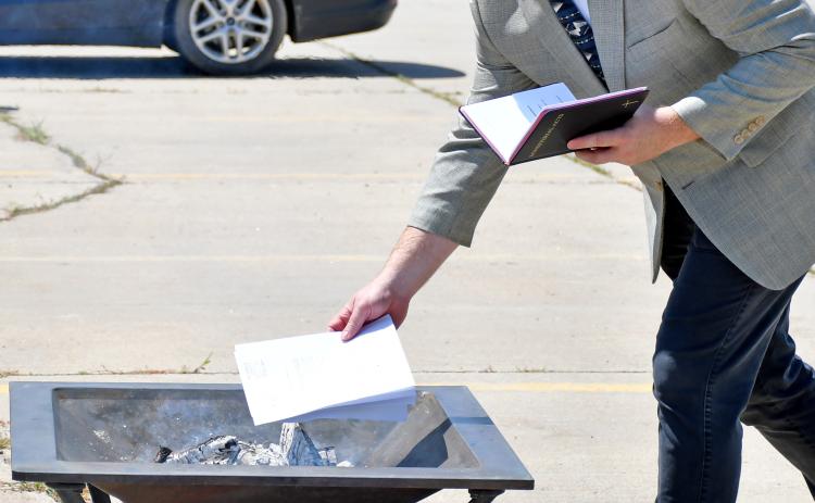 Reverend Dr. Jason Holt, a Presidential Ministry Associate with American Free Lutheran Church Congregations, places the paid off mortgage paperwork for Tabor Lutheran Church in Webster in a fire pit during a mortgage burning ceremony July 14. The church purchased what was formerly Shopko along U.S. Hwy. 12 in Webster and converted it to their worship center, paying down the 20-year loan in four and a half years, to the day. Reporter &amp; Farmer | Amanda Dulitz